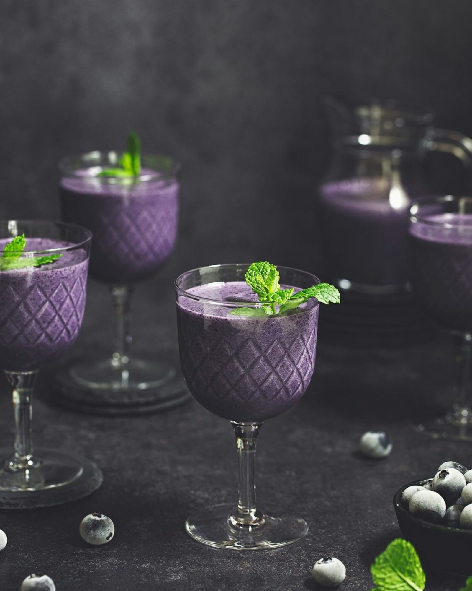 A table topped with glasses filled with purple drinks